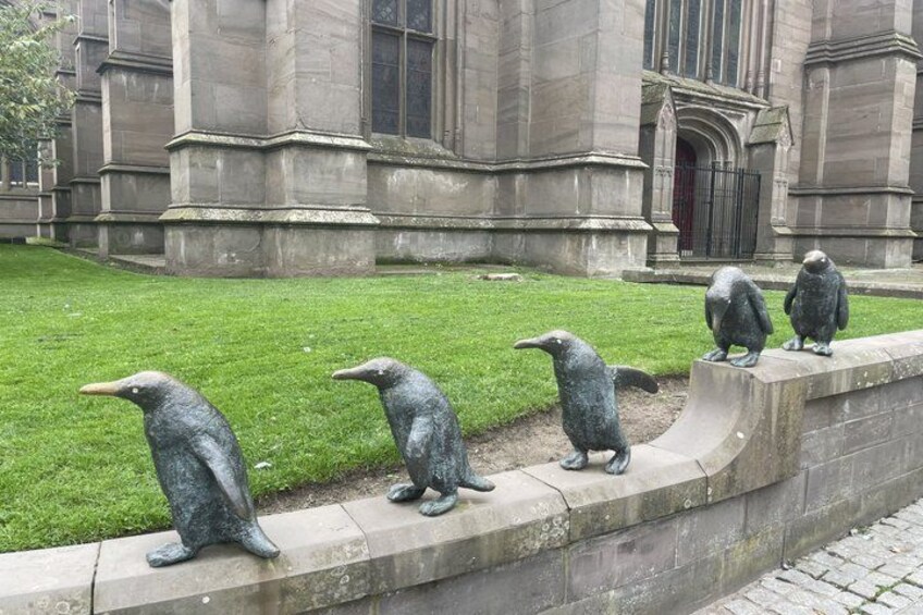 A row of penguin sculptures on a concrete ledge in front of a building. 1