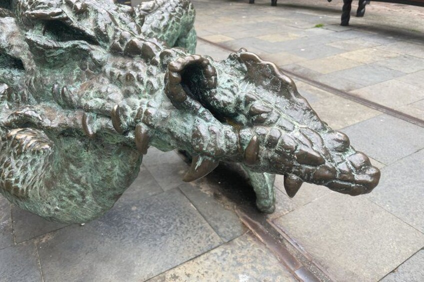 A bronze crocodile sculpture on a paved surface. 2