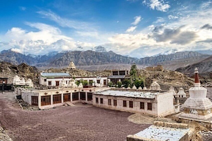 A monastery complex with buildings and a stupa in a mountainous landscape. 2