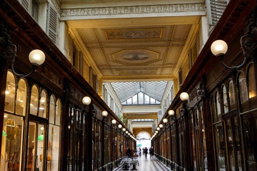 An indoor corridor with high ceilings, ornate woodwork, and large windows. 2
