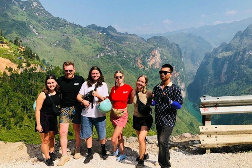 Un grupo de personas se encuentra sobre un sendero de montaña, disfrutando de una vista panorámica de valles verdes y acantilados. 2