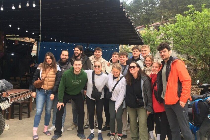 Un grupo de personas posando en un entorno al aire libre con una estructura cubierta y luces colgantes al fondo. 4