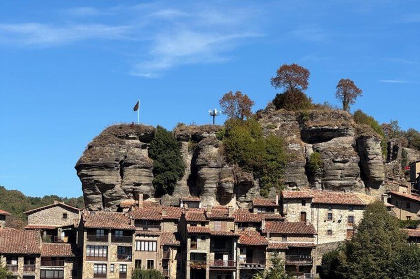 A village built on rocky cliffs with traditional buildings and a flag on top. 1