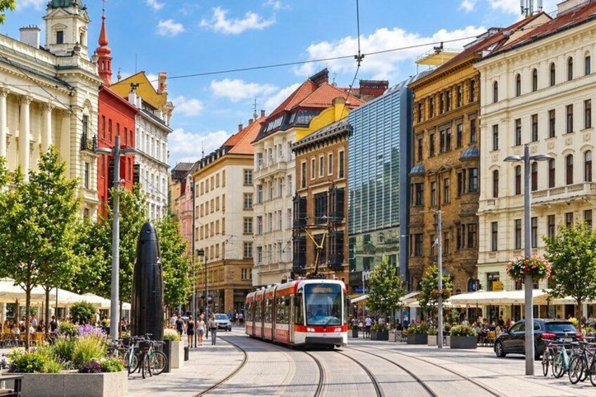 A tram on tracks, historic buildings, and a statue. 2