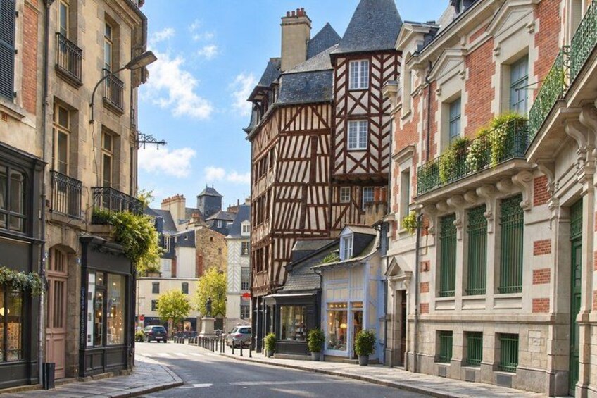 A street with historic buildings, a clear sky, and a parked car. 5