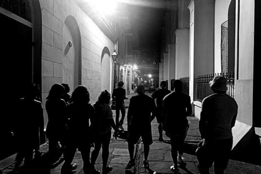 A nighttime street scene with people walking and standing. 2