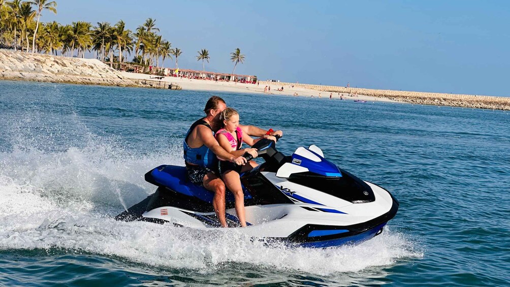 A person riding a jet ski on calm water with a beach and palm trees in the background. 5