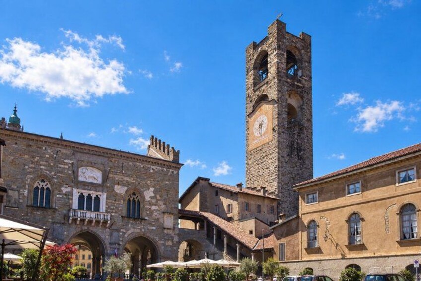 A historic building with a clock tower, arched windows, and a courtyard with outdoor seating. 4