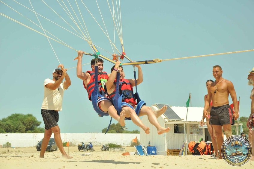 Twee personen in een harnas die door een parachute omhoog worden getild. 1