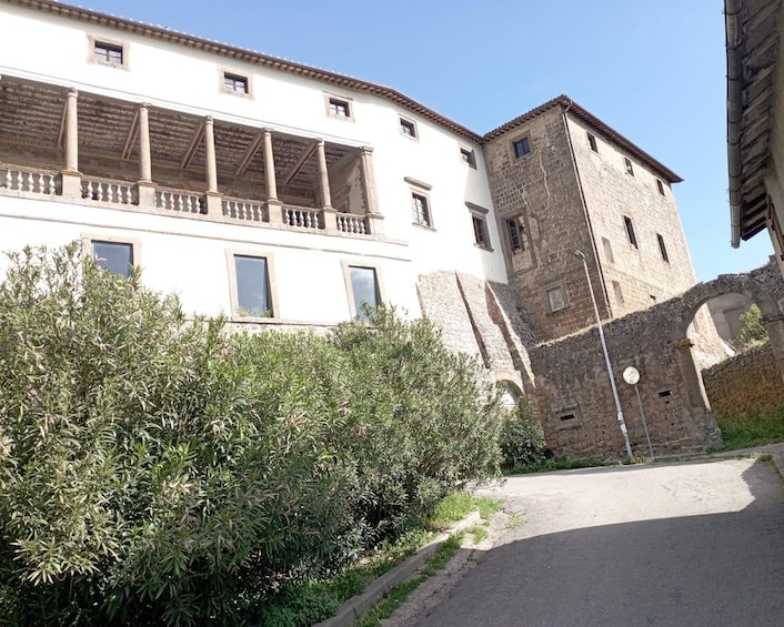 A white building with a balcony, a stone tower, and a paved road. 4