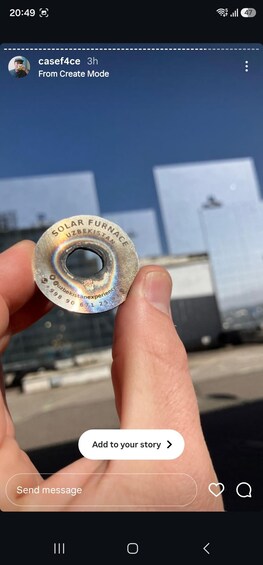 Eine Hand hält ein metallisches Objekt mit Text vor unscharfem Hintergrund. 2