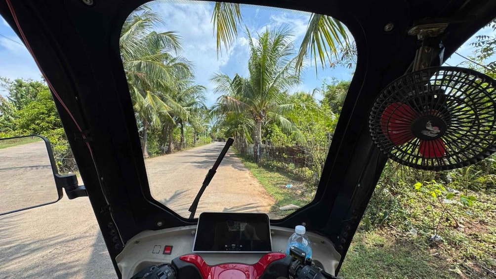 Het interieur van een voertuig, met uitzicht op een weg met palmbomen. 3