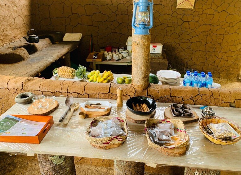 A rustic outdoor dining setup with stone walls, a wooden table, and various food items and utensils. 3