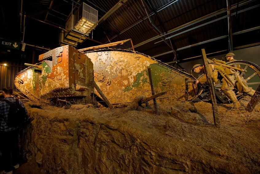A large, rusted, cylindrical tank with a ladder and a wheel mechanism, surrounded by a sandy environment. 3