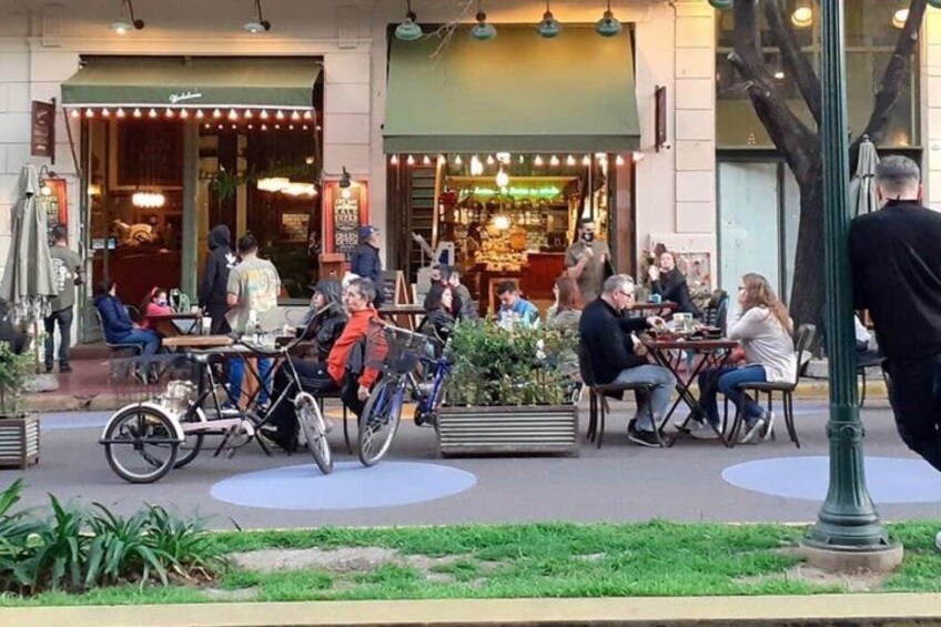An outdoor cafe with people dining and bicycles parked. 5