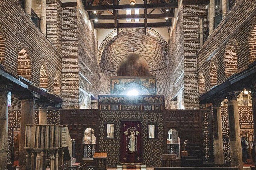 An interior of a historical building with brick arches, a central dome, and intricate wall patterns. 3