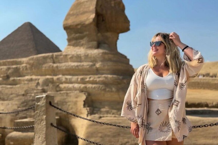 A person standing in front of the Great Sphinx of Giza, with the Pyramid of Khafra in the background. 1