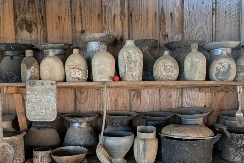 A collection of variously shaped and sized pottery items, including pots, vases, and bowls, displayed on wooden shelves against a wooden wall. 4
