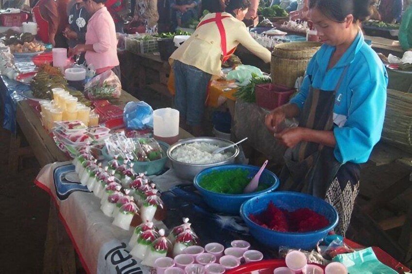 A market stall with various food items and a person preparing food. 2