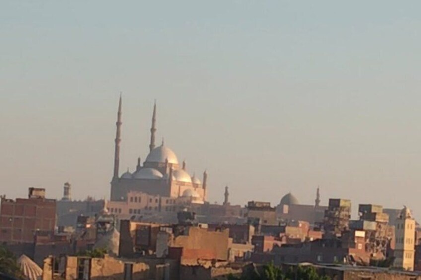 Una mezquita con una cúpula grande y dos minaretes, rodeada de edificios urbanos. 3