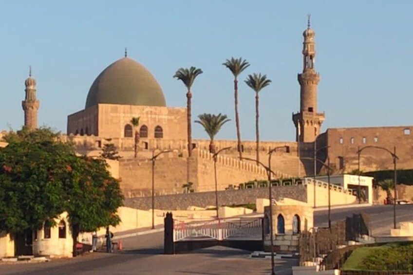 Una mezquita con una cúpula grande y minaretes, palmeras y cielo despejado. 2