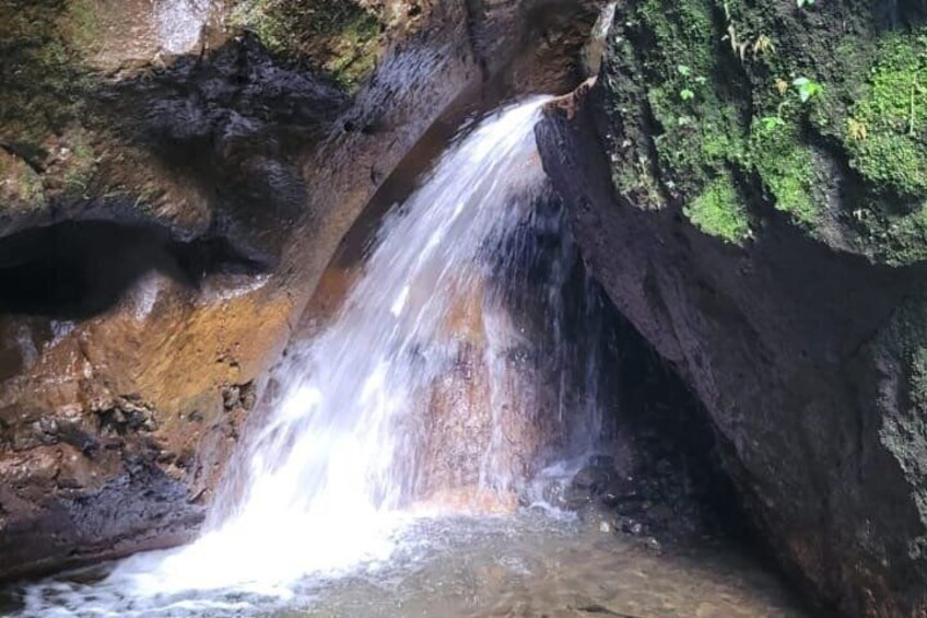 A waterfall cascading over rocks in a forested area. 1