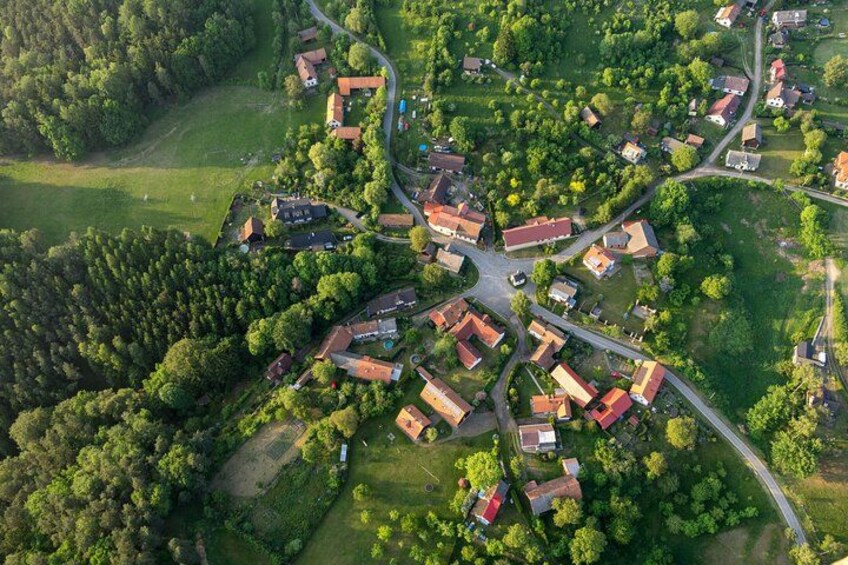 An aerial view of a village with houses, roads, and surrounding greenery. 5
