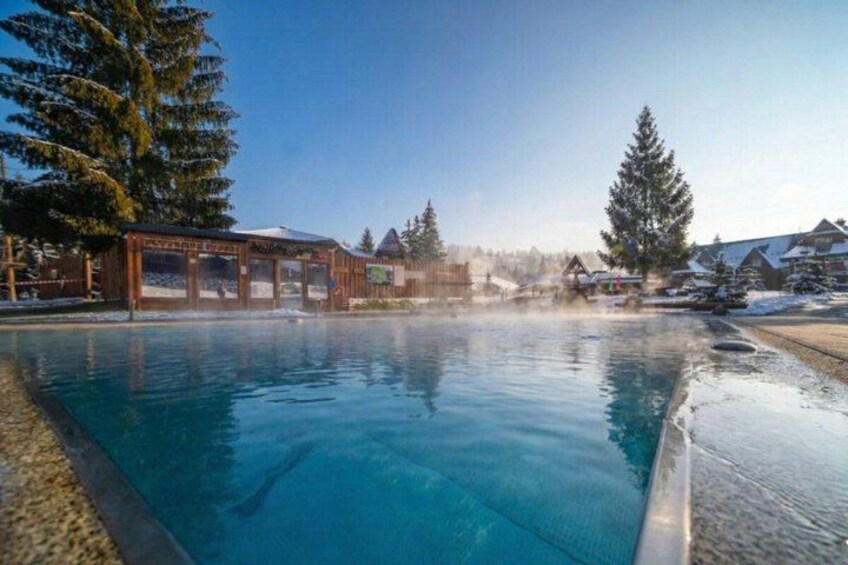 A clear blue pool with wooden structures and snow-covered trees in the background. 5