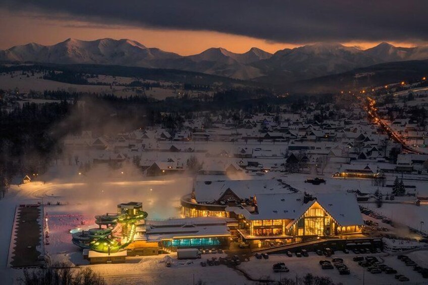 A snow-covered village with illuminated buildings and mountains in the background. 4