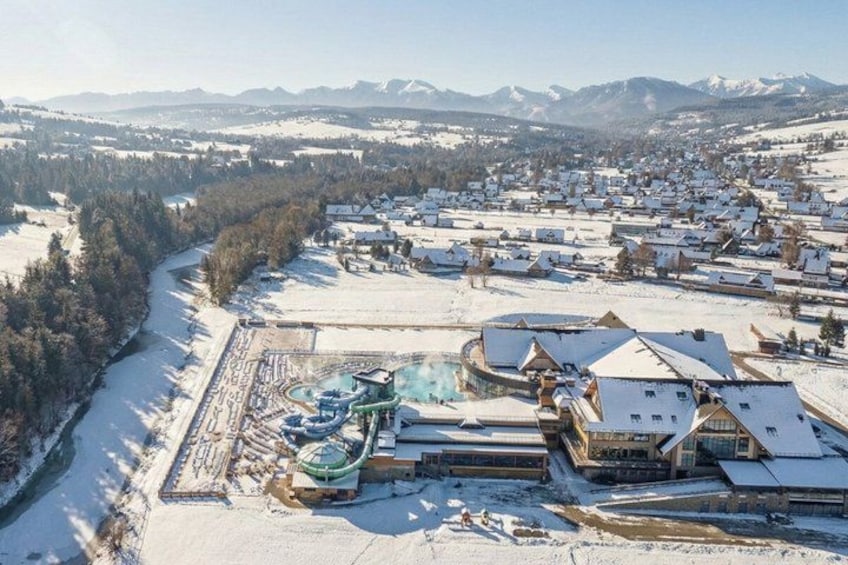 A snowy landscape with a ski resort, buildings, and mountains in the background. 3
