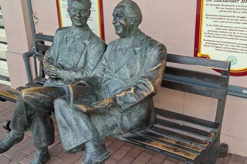 A statue of two men seated on a bench. 3