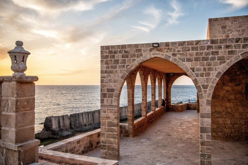 Un camino de piedra que lleva a vistas del mar, con arcos y un farol. 2
