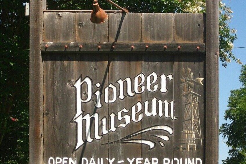 A wooden sign with the text 'Pioneer Museum' and 'OPEN DAILY YEAR ROUND' indicating the museum's name and operating hours. 5