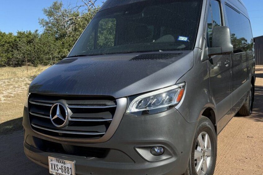 A gray Mercedes-Benz van parked on a dirt road with a clear blue sky in the background. 4