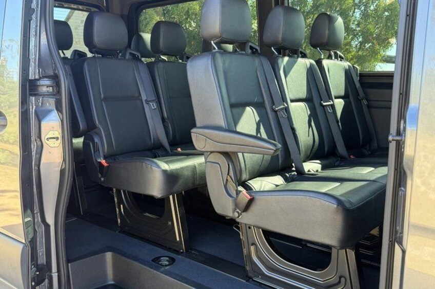 A vehicle interior with three rows of seats, a center console, and a rear storage compartment. 3