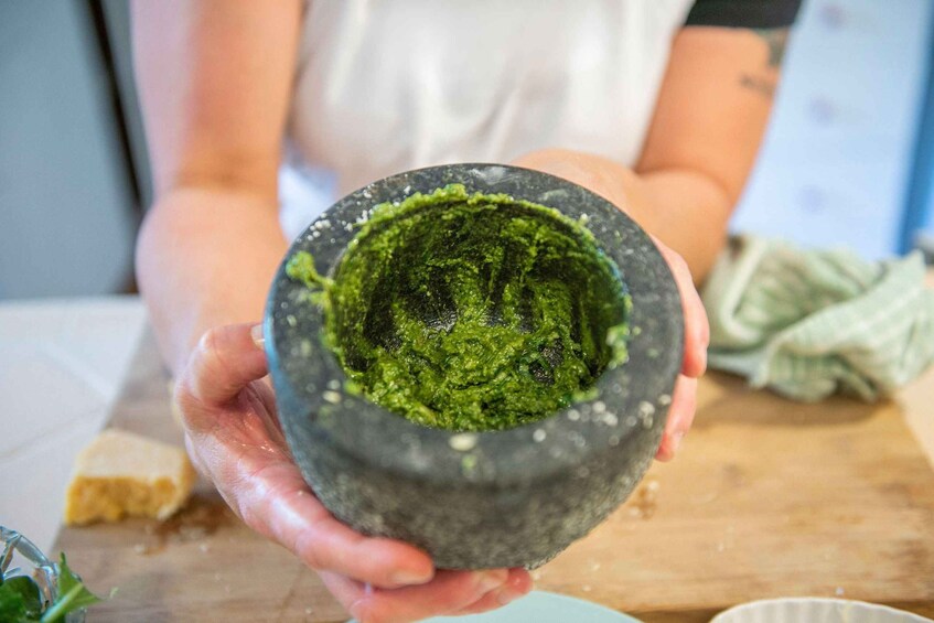 A person holding a mortar with green contents. 4