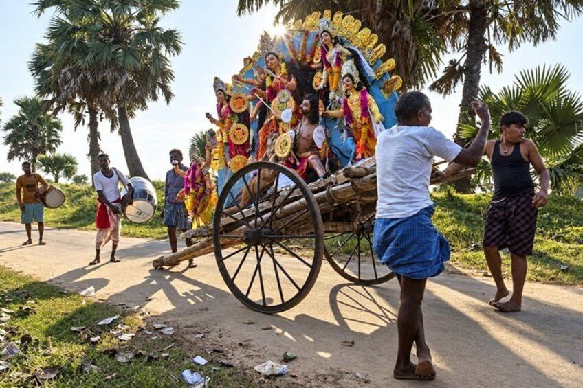 A procession with a decorated cart, palm trees, and people in traditional attire. 2