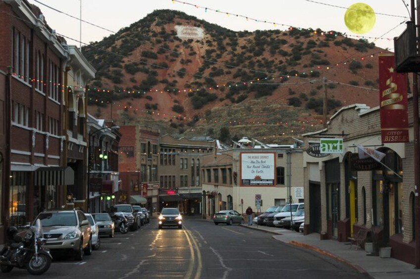 A street with parked cars, buildings, and a mountain in the background. 4