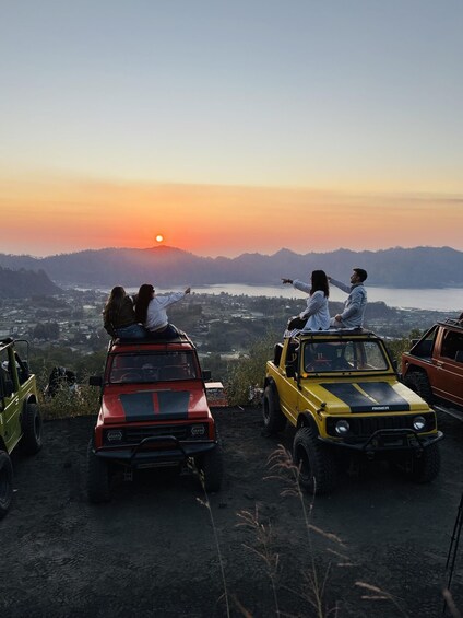 Solnedgang over et dalstrøg med en gruppe mennesker i jeeps på en bakke. 5