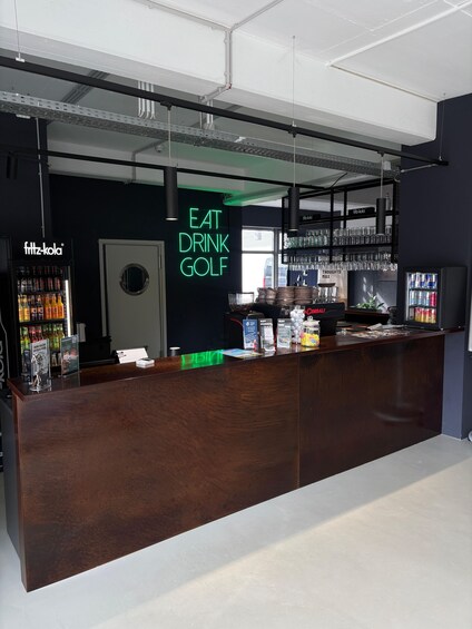 A modern bar with a neon sign reading 'EAT DRINK GOLF'. 5