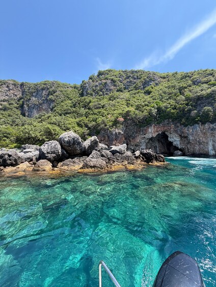 Mare turchese cristallino, costa rocciosa e montagne sullo sfondo. 4
