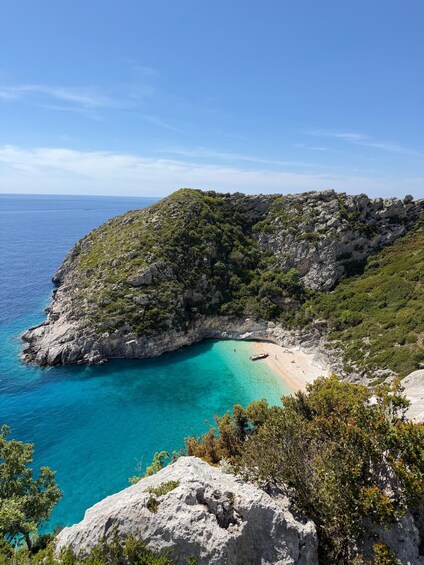Paesaggio costiero con mare cristallino, spiaggia sabbiosa, scogliere rocciose e vegetazione rigogliosa. 2