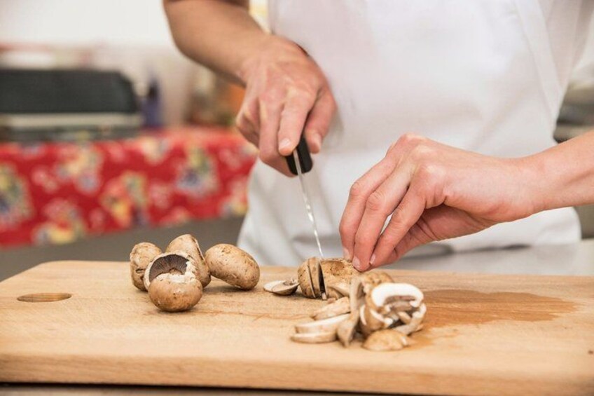 A person slicing mushrooms on a wooden cutting board. 5