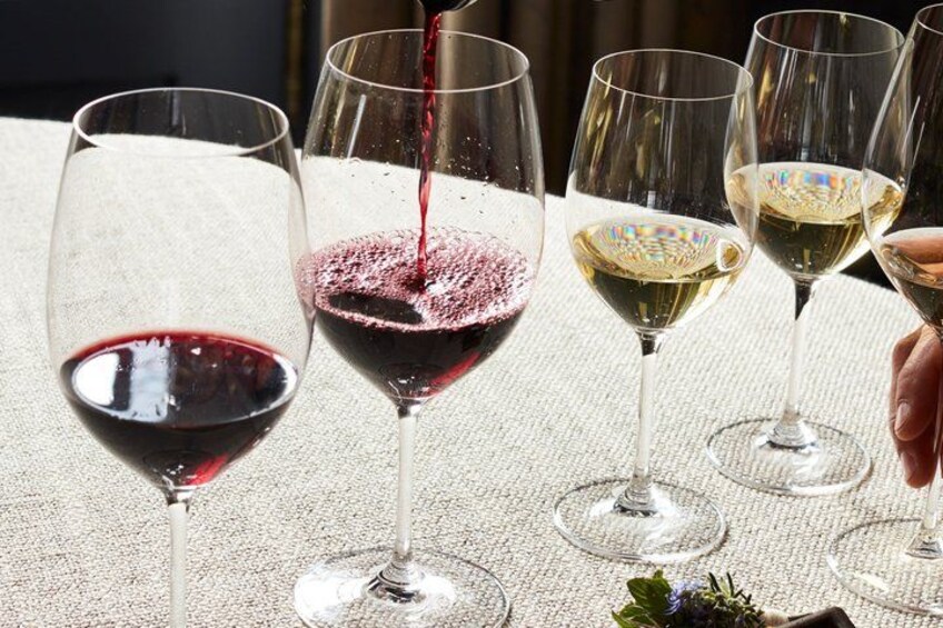 Wine glasses on a table with red and white wine being poured. 4