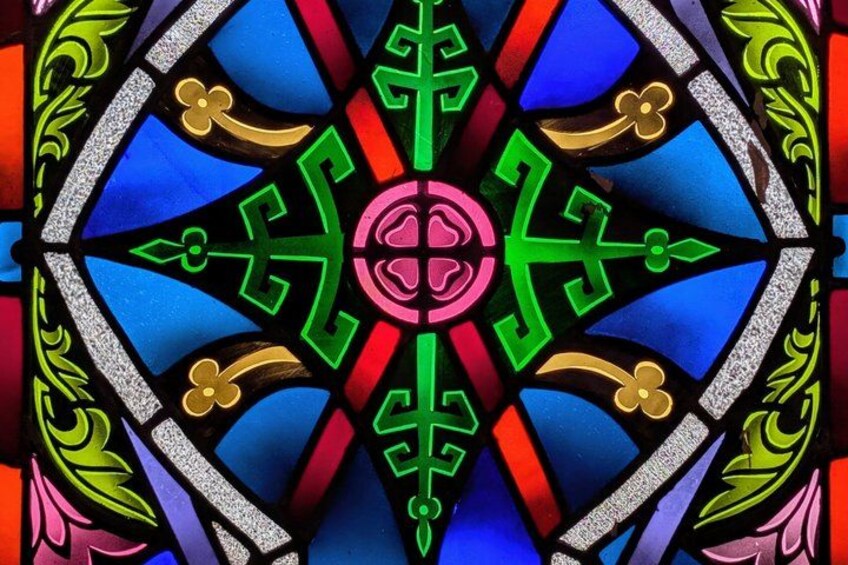 A stained glass window with a geometric pattern, featuring blue, red, green, and pink colors. 4
