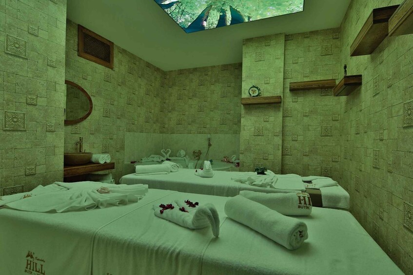 A spa room with two beds, a sink, and a mirror. 2