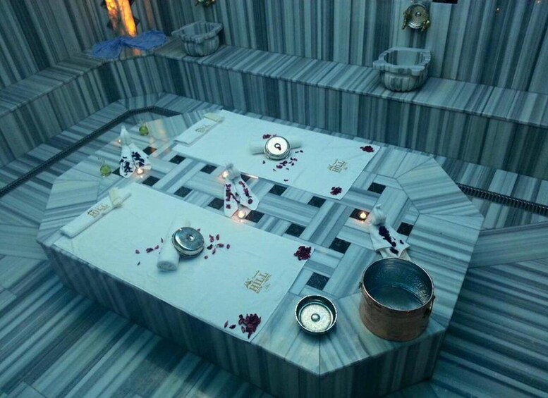 A room with a patterned floor, a table with a white cloth, and various objects including a metal bowl, a candle, and a decorative item. 1