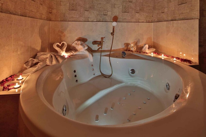 A hot tub with heart-shaped towels, candles, and rose petals. 4
