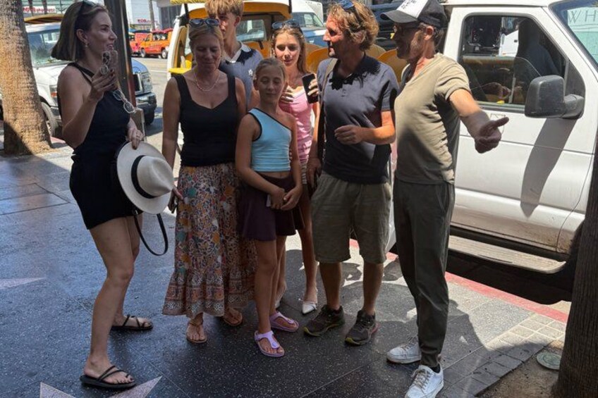 A group of people standing on a sidewalk near a parked vehicle. 5