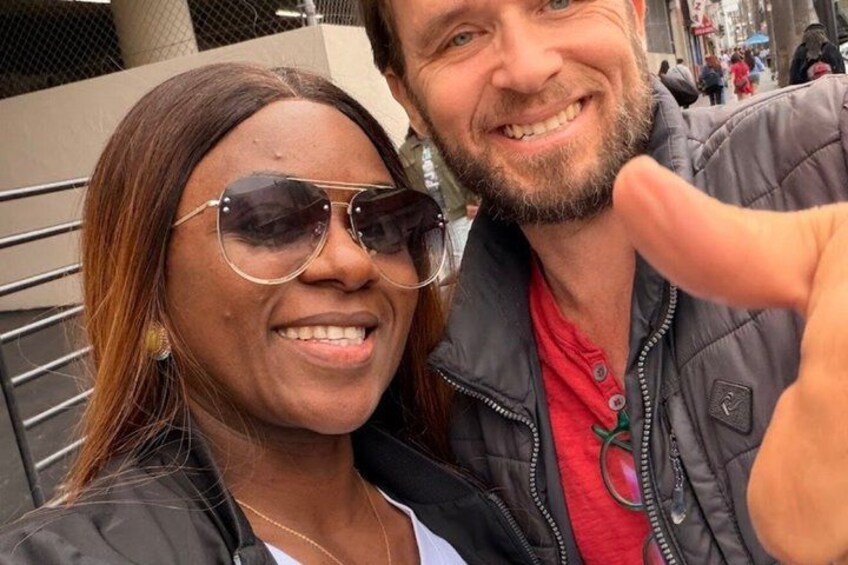 Two people taking a selfie with a metal railing and a building in the background. 3